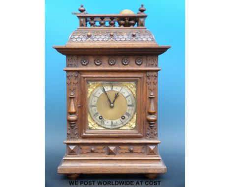 An oak cased mantel clock with bobbin turned gallery finial, silvered chapter ring to cherub spandrelled dial and beetle and 