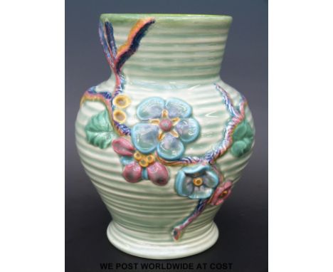 A Clarice Cliff Newport Pottery vase with moulded decoration of flowers and vines over ribbed green ground (17.5cm tall)