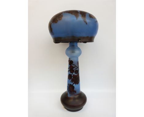An overlaid cameo glass table lamp with red floral decoration over blue ground, signed to the shade Galle, 67cm tall. 
