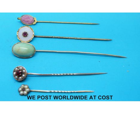 Five yellow metal stick pins, two set with seed pearls and a garnet and one set with a turquoise cabochon