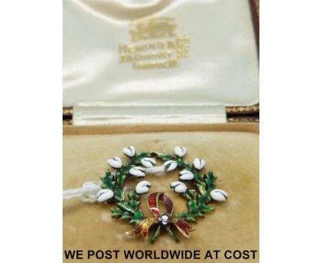 A yellow metal brooch set with enamel in the form of a wreath with a diamond set bow to the bottom, in original box for Hemin