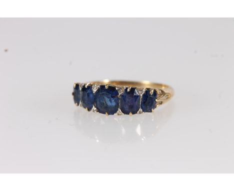 Victorian five stone sapphire ring, the graduating cushion cut sapphires interspersed with diamond chips on scrolled mount, t