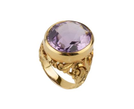 An amethyst single stone dress ring, the oval mixed-cut amethyst in collet setting, above a foliate scroll decorated gallery 