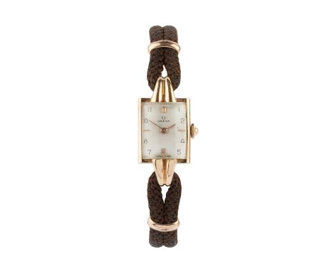 A lady's wristwatch by Omega, the rectangular silvered dial with gilt baton quarters and Arabic numerals, to a jewelled manua