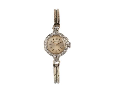 A diamond cocktail watch by Vertex, the circular dial with black insert baton markers, to a foliate scroll engraved case with