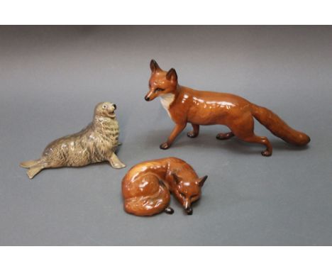 Three Beswick figures, standing fox, lying fox, and a seal, model No. 1534.