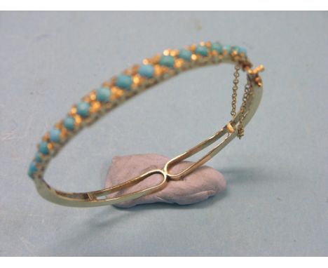 An Edwardian yellow metal bangle, half-hoop design set seventeen graduated turquoises