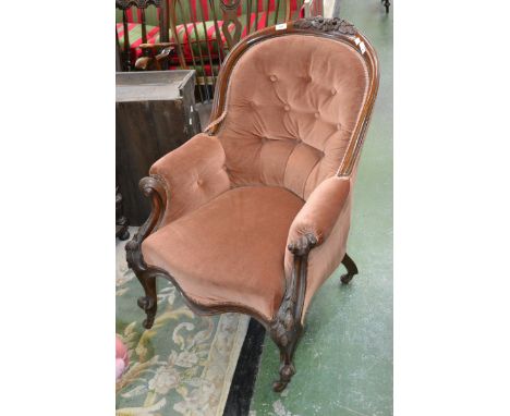 A Victorian mahogany button back armchair, floral carving to top rail, padded arms, serpentine stuffed overseat, carved cabri