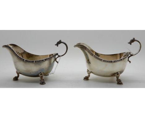 A pair of silver sauceboats, Birmingham 1937, with Celtic decoration, the scrolling handle termination in mythical beasts hea