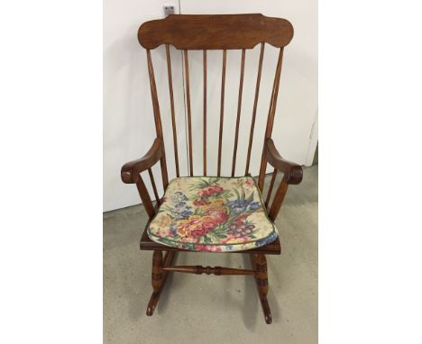 Modern oak stick back rocking chair with floral cushion.