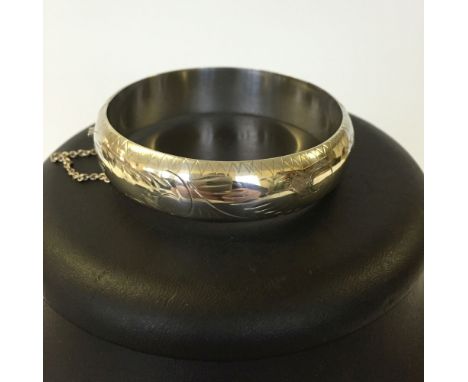 Hallmarked silver hinged bangle with contemporary style engraving and safety chain. Depth approx 1.5cm, weight approx 24.5g