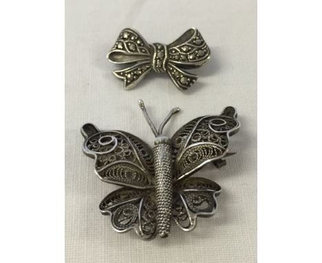 2 pretty brooches, 1 in the shape of a butterfly with filligree work and the other a bow set with marcasite.