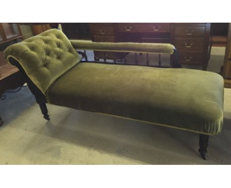 A Victorian chaise longue with turned legs, ceramic casters, spindle rail and green velvet upholstery.