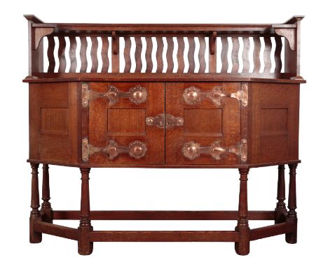 ATTRIBUTED TO LIBERTY & CO: AN ARTS AND CRAFTS OAK SIDEBOARD shaped rectangular top, above an upright gallery back and shelf,