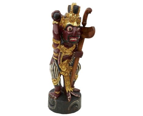the carved wooden warrior figure painted and highlighted in gilt and holding a full sized kris in its left hand.