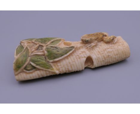 A carved bone netsuke decorated with a frog. 6 cm high.