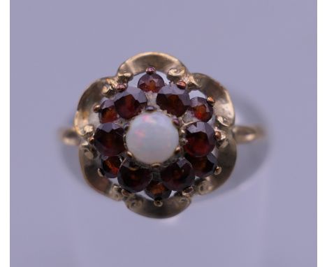 An unmarked 9 ct gold garnet and opal ring. Ring size M. 1.6 grammes total weight.