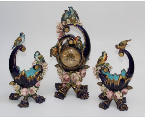 A circa 1900's French porcelain mantle clock of organic form, applied with roses and songbirds containing an eight day bell s