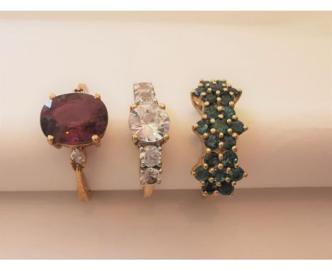 Three 20th century 10 carat yellow gold gem-set rings: a tourmaline triple floral cluster ring, a cubic zirconia flanked soli