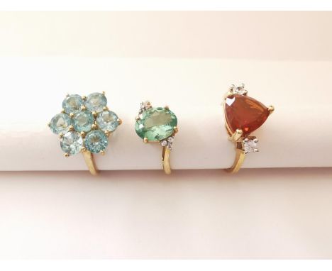 Three 20th century 10 carat gold gem-set rings: a fire opal and cubic zirconia flanked solitaire ring, a blue stone floral cl