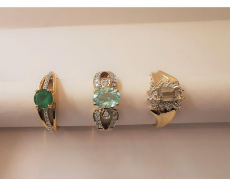 Three 20th century 18 carat yellow gold gem-set rings: a diamond and emerald flanked solitaire ring, a diamond and Prasiolite