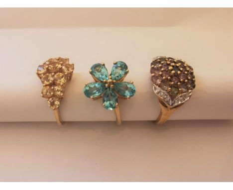 Three 20th century 9 carat and 10 carat yellow gold gem-set rings: a blue topaz floral ring, a tourmaline and diamond cluster