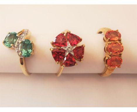 Three 20th century 9 carat and 10 carat yellow gold gem-set rings: a tourmaline and diamond cross over ring, a three stone or