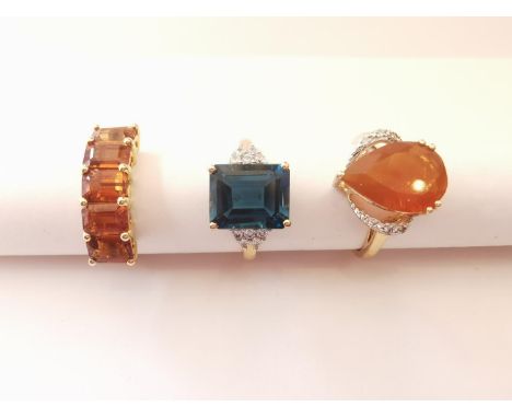 Three 20th century 10 carat gold gem-set rings: a blue topaz flanked solitaire ring, a diamond and fire opal drop shaped soli