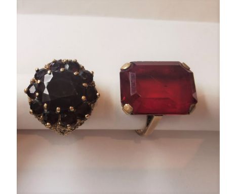 Two 9 carat yellow gold and red metal dress rings. One set with a large red paste stone, the other a garnet cluster ring with