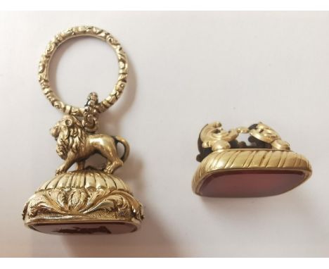 Two Victorian yellow metal plated fob seals, one with a carved lion finial and scrolling foliate design to the border and han