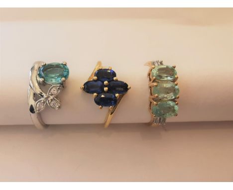 Three 20th century 10 carat white gold gem-set rings: a floral design sapphire ring, a blue topaz foliate design ring and a t