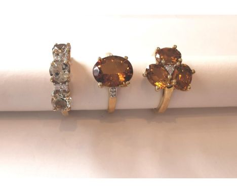 Three 20th century 10 carat yellow gold gem-set rings: a three stone Prasiolite dress ring, a topaz and diamond flanked solit