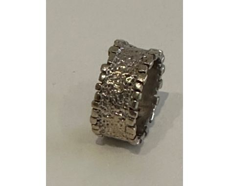 A bark textured brutalist design 9 carat white gold band. Hallmarked 9 carat and with indistinct makers mark. Weight 7.39g. R