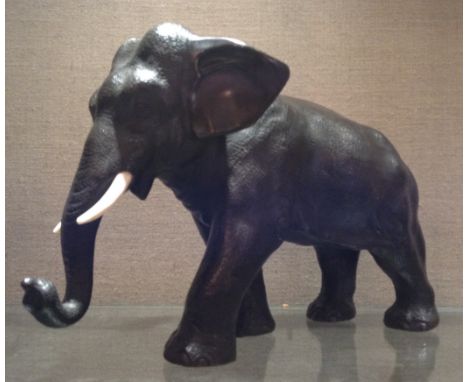 A 19TH CENTURY MEIJI PERIOD JAPANESE BRONZE ELEPHANT  With ivory tusks, in a walking pose and complete with a textured finish