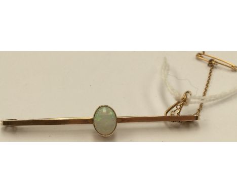 An opal and yellow metal (probably 9ct gold) bar brooch, comprising a central oval white solid opal with green/blue and red f