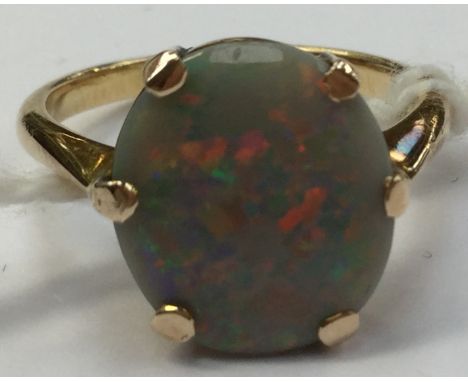 An opal ring, the opal with a base of grey displaying red, blue and green fire, approx stone size 9mm x 11mm, claw set in yel