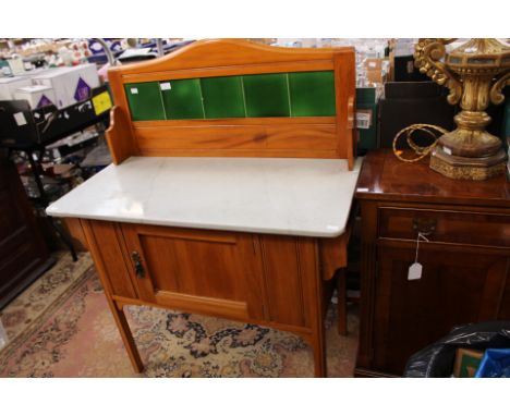 An Edwardian satinwood tile backed washstand, the back with green glazed tiles, marble top, fitted with a single door, standi