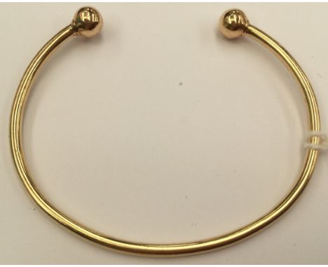 A 9ct gold torque bangle, hollow round section with a ball bead detail to each end, approx diameter 60mm,  weighing approx 10