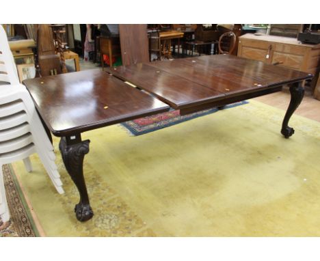 A Chippendale style mahogany extending dining table, complete with extra leaves, standing on cabriole legs, with claw and bal