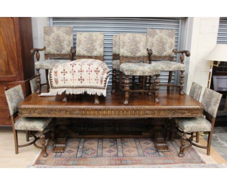 A 1920s oak dining table, with a carved frieze, raised on cup and cover supports, together with a set of ten chairs, comprisi