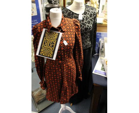A black lace 1929/1930 evening frock, the top has a low waist, long sleeves and the skirt has a tiered detail onto the hem (t