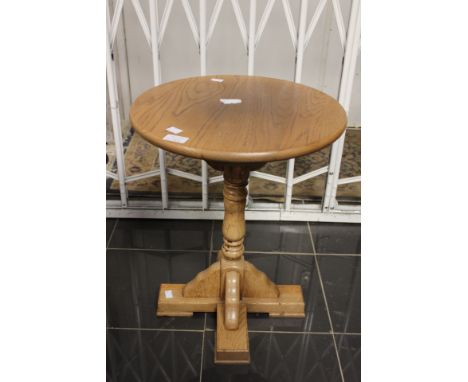 A contemporary oak pedestal circular topped table