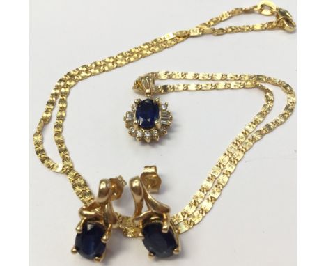 A 14k sapphire and diamond cluster pendant with a central oval sapphire with a surround of  brilliant and baguette cut diamon