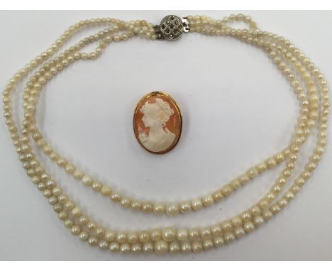 A gold mounted cameo brooch, depicting female figure with a 9ct gold surround, along with a three strand graduated pearl neck