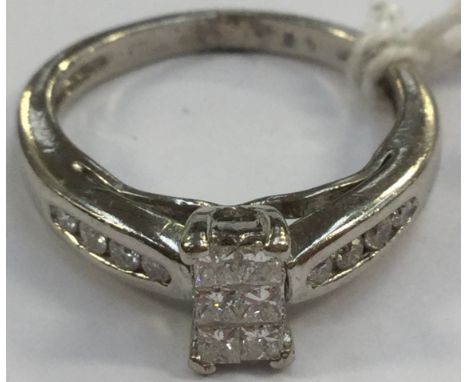 A diamond ring, set with six princess cut diamonds, in a rectangular setting, with further small brilliant cut diamonds, chan