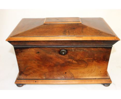 An early 19th century, large mahogany sarcophagus tea caddy with contents raised on squat ball feet  