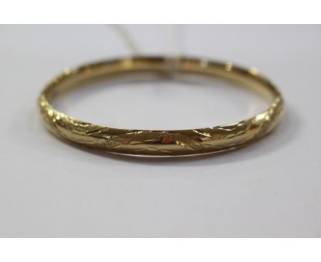 A 9ct gold hinged bangle, with engraved floral motif pattern, approx 6 mm wide, with a weight of approx 7.3 grams 