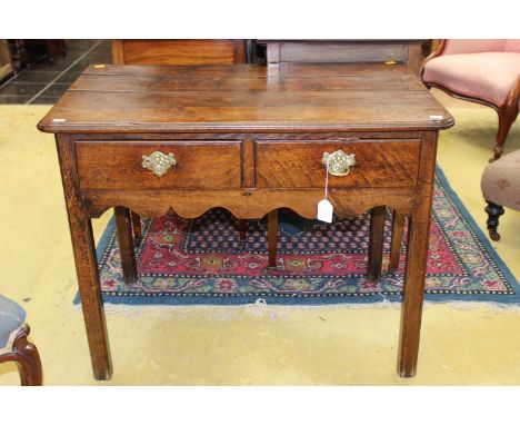 A George III oak side table, fitted with two drawers, raised on square legs