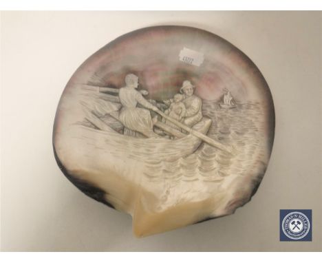 A relief carved mother of pearl shell depicting a family in a rowing boat, width 19cm