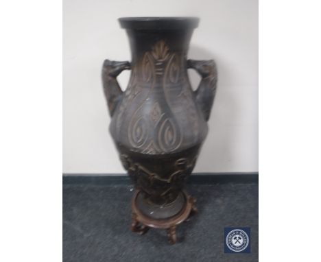 A large pottery vase with horse head handles, on stand